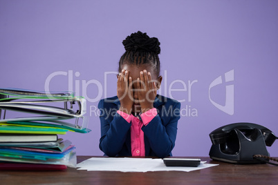 Businesswoman covering eyes while sitting at desk