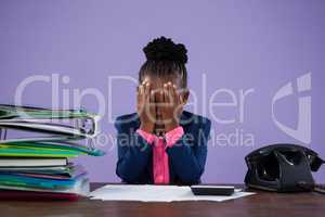 Businesswoman covering eyes while sitting at desk