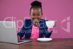 Portrait of happy businesswoman with laptop having coffee