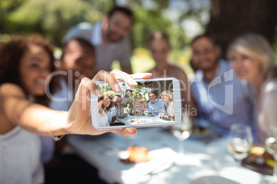 Friends taking selfie on mobile phone while having meal