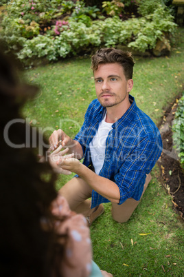 Handsome man wearing engagement ring to woman