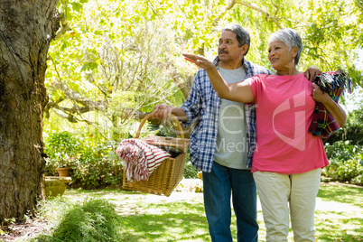 Senior couple walking in garden with basket