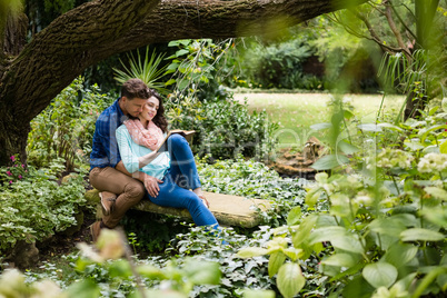 Romantic couple reading book on bench in garden