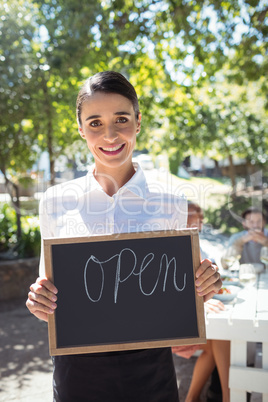 Smiling waitress standing with open sign board