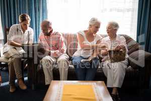 Female doctor reading book with man while senior women talking against window