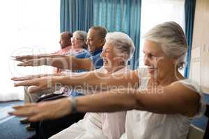 Cheerful senior people exercising with arms raised