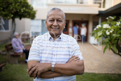 Portrait of smiling senior man standing with arms crossed