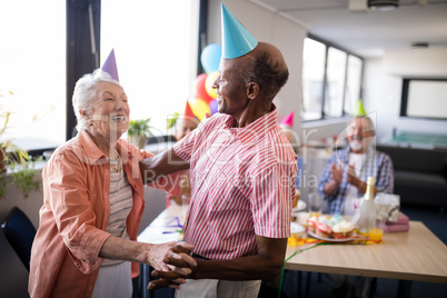 Senior couple wearing party hats dancing at birthday party