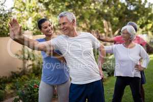 Happy trainer teaching senior people while exercising