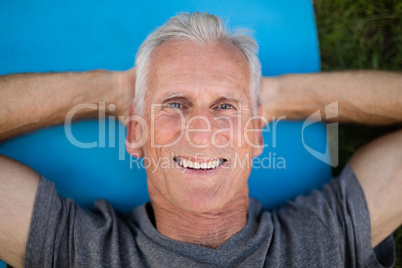 Portrait of smiling senior man lying on exercise mat