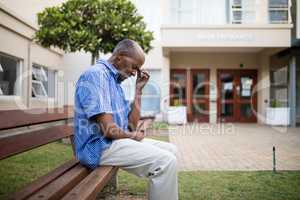 Sad senior man sitting on wooden bench