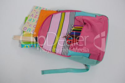 Schoolbag with various supplies on white background