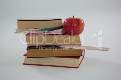 Books, color pencils, scale and apple on white background