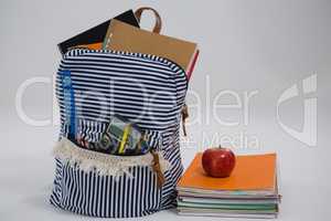 Schoolbag, apple and book stack on white background