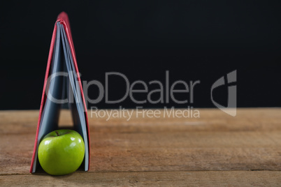 Apple and book on wooden table
