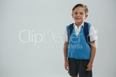 Cute schoolboy standing against white background