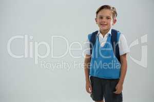 Cute schoolboy standing against white background