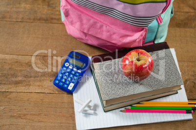 School supplies, books stack with red apple on wooden table