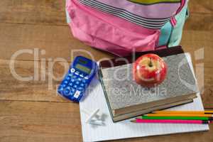 School supplies, books stack with red apple on wooden table