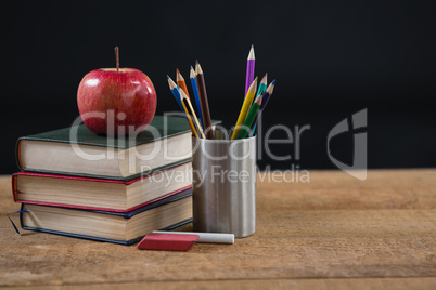 School supplies and books stack with red apple on top