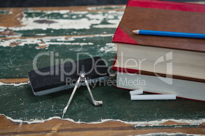 Books, duster and compass on wooden table