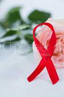 Close-up of red AIDS ribbon with pink rose