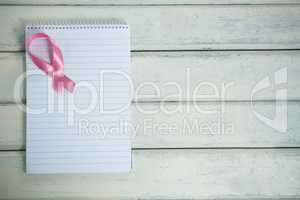 Directly above view of pink Breast Cancer Awareness ribbon and spiral notepad