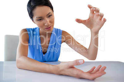 Businesswoman gesturing while holding something at table