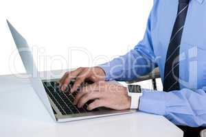 Mid section of businessman using laptop while sitting at table