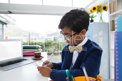 Businessman wearing eyeglasses while writing on paper