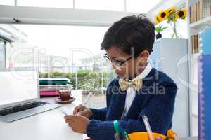 Businessman wearing eyeglasses while writing on paper