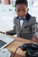 Serious businessman with telephone and laptop at desk