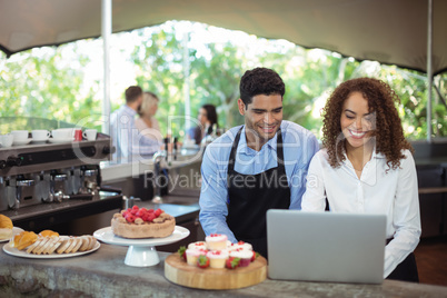 Male waiter and female waitress with laptop