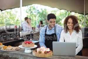 Male waiter and female waitress with laptop