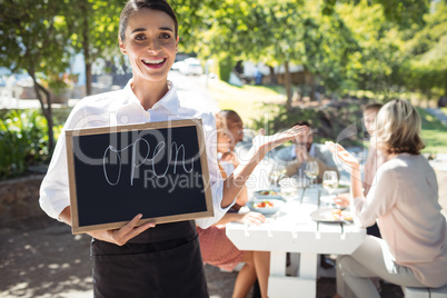 Smiling waitress standing with open sign board