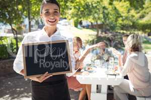 Smiling waitress standing with open sign board