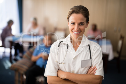 Portrait of smiling female doctor standing with arms crossed