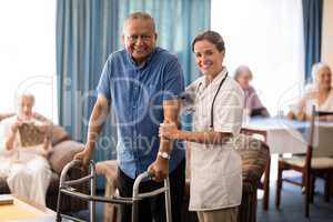 Portrait of smiling female doctor standing by senior man with walker