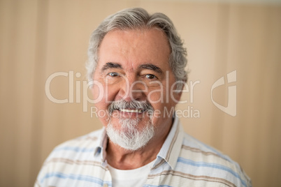 Close-up portrait of senior man against wall
