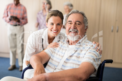 Portrait of smiling female doctor with disabled senior man sitting on wheelchair