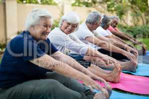 Cheerful senior woman with friends doing stretching exercise