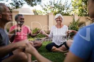 Smiling senior people meditating with trainer while holding hands