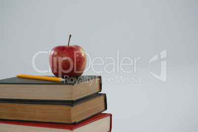 Apple and pencil on book stack