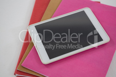 Digital tablet on book stack on white background