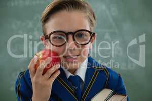 Schoolboy holding red apple against chalkboard