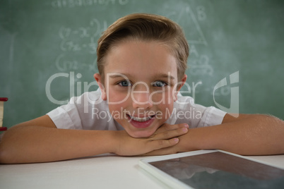 Schoolboy relaxing on table in classroom