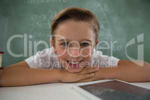 Schoolboy relaxing on table in classroom