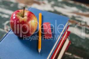 Apple, pencil and eraser on stack of books