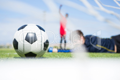 Goalkeeper lying on field while playing soccer