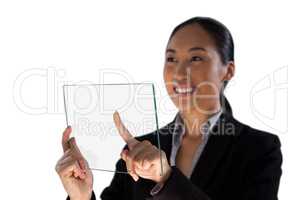 Smiling businesswoman looking away while touching glass interface